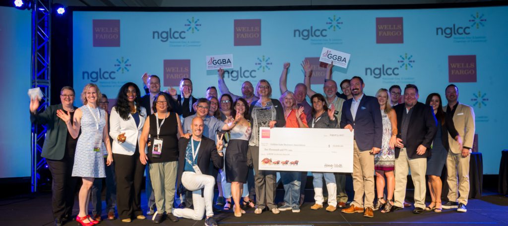 A group of people pose with a large check onstage at an NGLCC and Wells Fargo event.