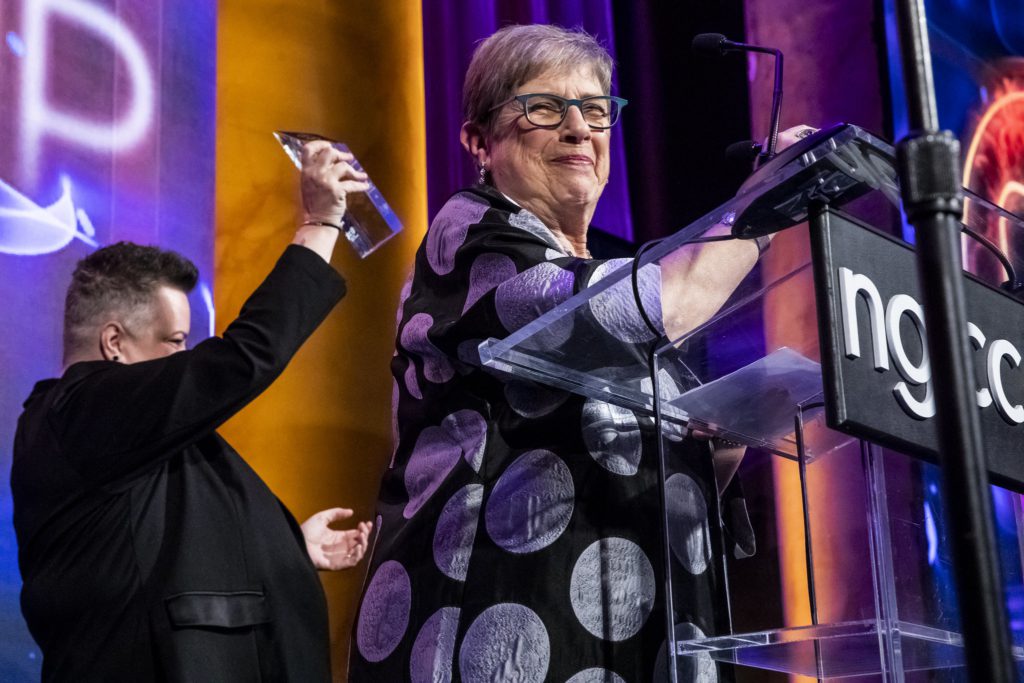 A woman smiles behind the podium onstage at an NGLCC event. CEO of GSBA, Louise Cherniin, accepting the Affiliate Chamber of the Year Award at NGLCC's 2019 National Dinner