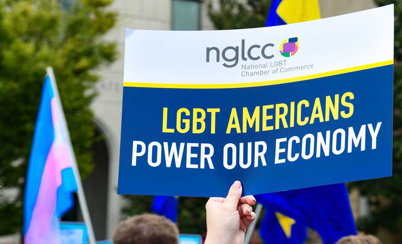 A person holding a sign that says "LGBT Americans power our economy".