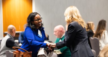 Two women shake hands at an NGLCC event